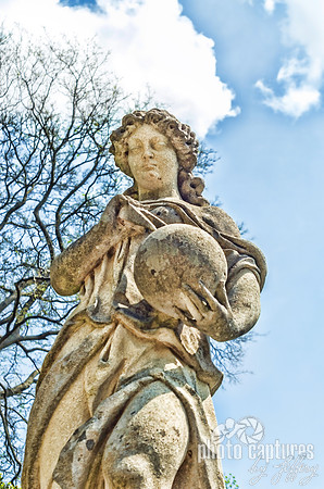 Lady Sculpture With Sphere Against Blue Sky