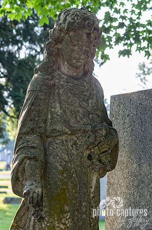 Solemn female sculpture next to headstone