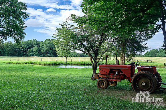 Old red farm tractor near pond