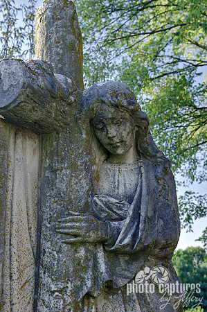 Female sculpture leaning on wood log cross